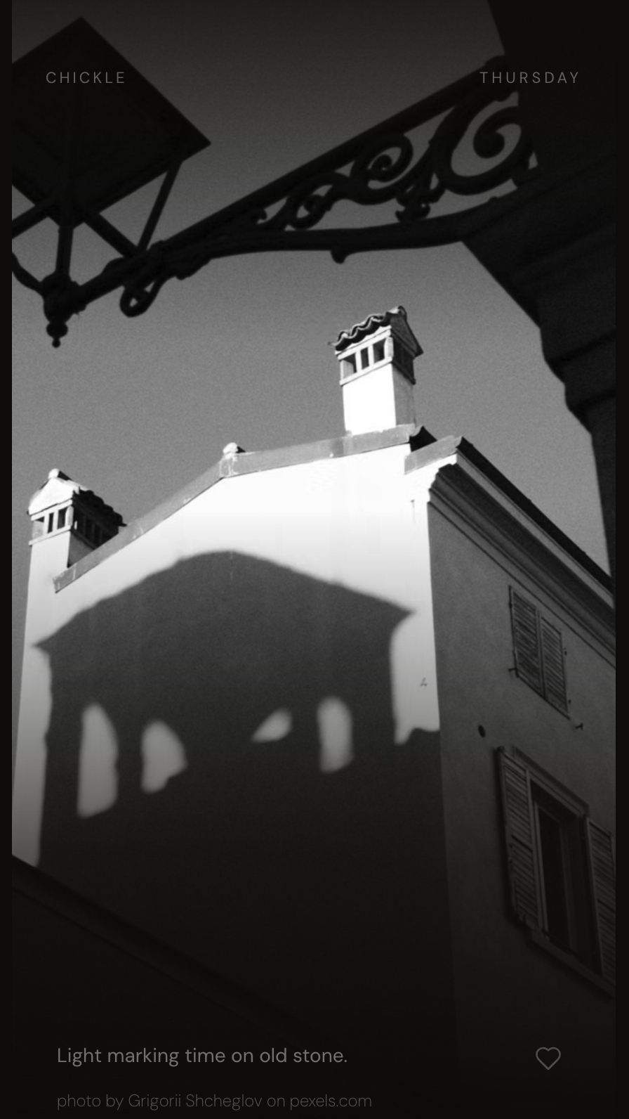 Chickle: shadow of a curly wrought-iron lamp on an old white building, with the caption 'Light marking time on old stone.'
